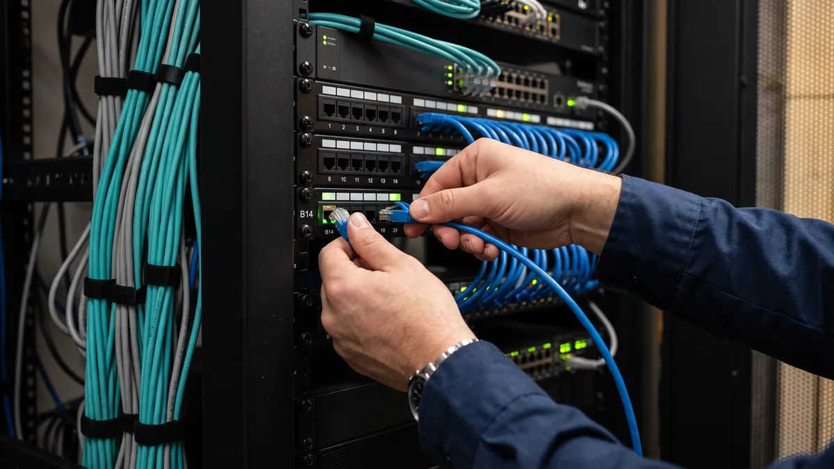 Technician seating a patch cable in a network closet as part of the network maintenance included in a managed IT contract